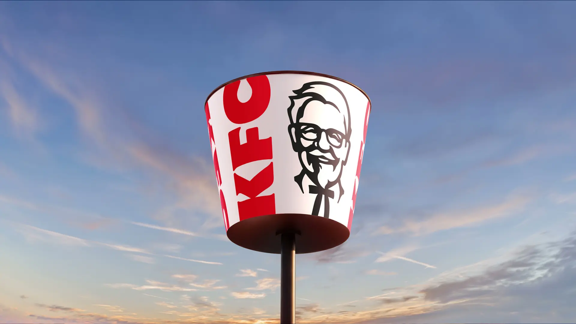 KFC bucket-shaped roadside sign on pole at sunset