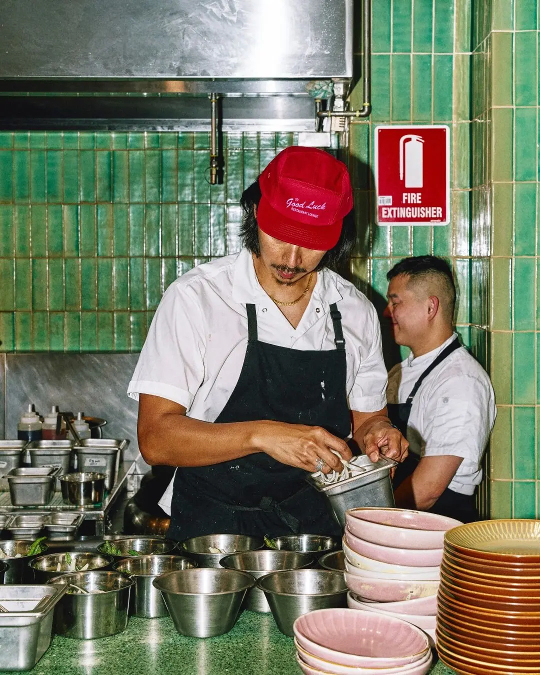 Chef at prep station with red "Good Luck" cap and stacked pink bowls