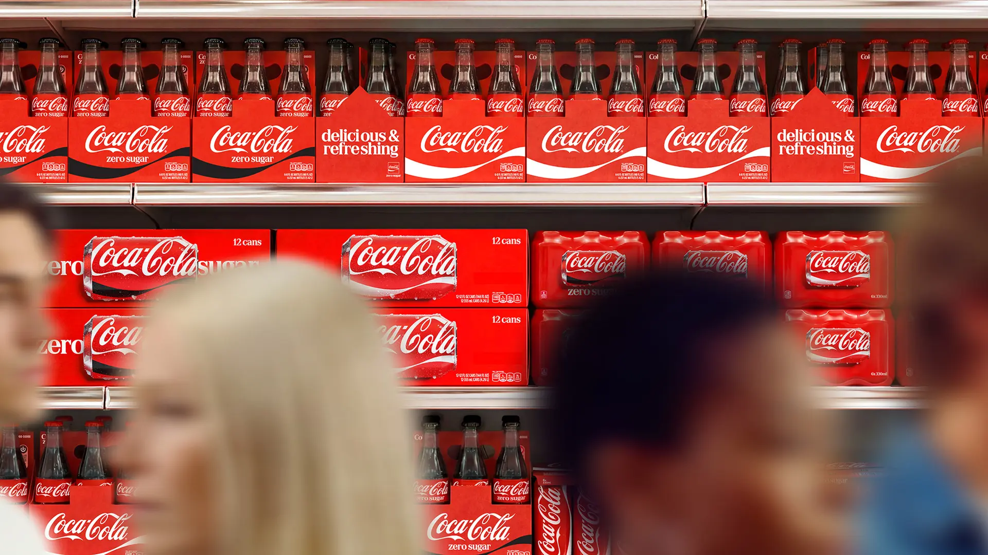 Coca‑Cola retail shelf display with red cans and glass bottles