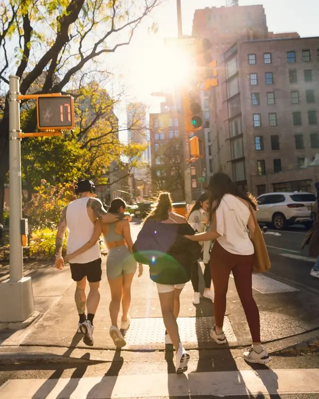 Friends crossing a sunlit city intersection — backlit street photo