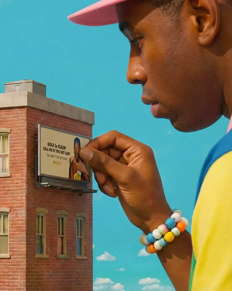Person placing GOLF le FLEUR billboard on miniature brick building