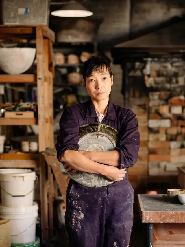 Potter in ceramic studio holding large glazed platter