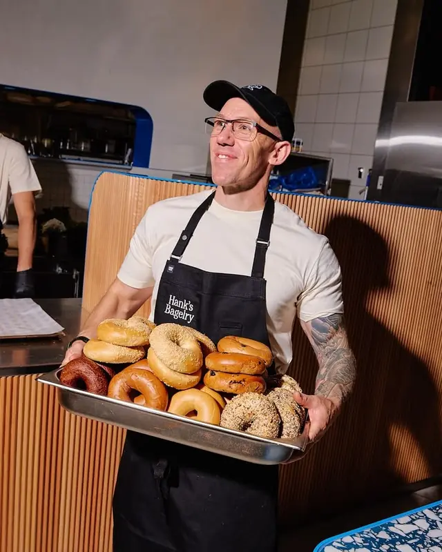 Employee holding tray of assorted bagels at Hank's Bagelry