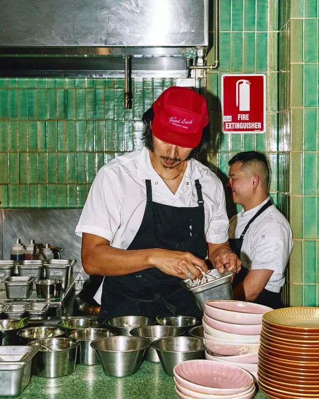 Chef at prep station with red "Good Luck" cap and stacked pink bowls