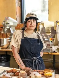 Artisan baker behind pastry-filled counter in sunlit bakery
