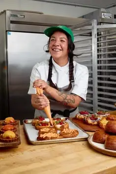 Baker piping cream on pastries in commercial bakery