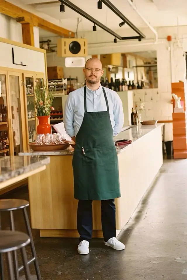 Shop staff in dark green apron behind marble-topped wooden counter
