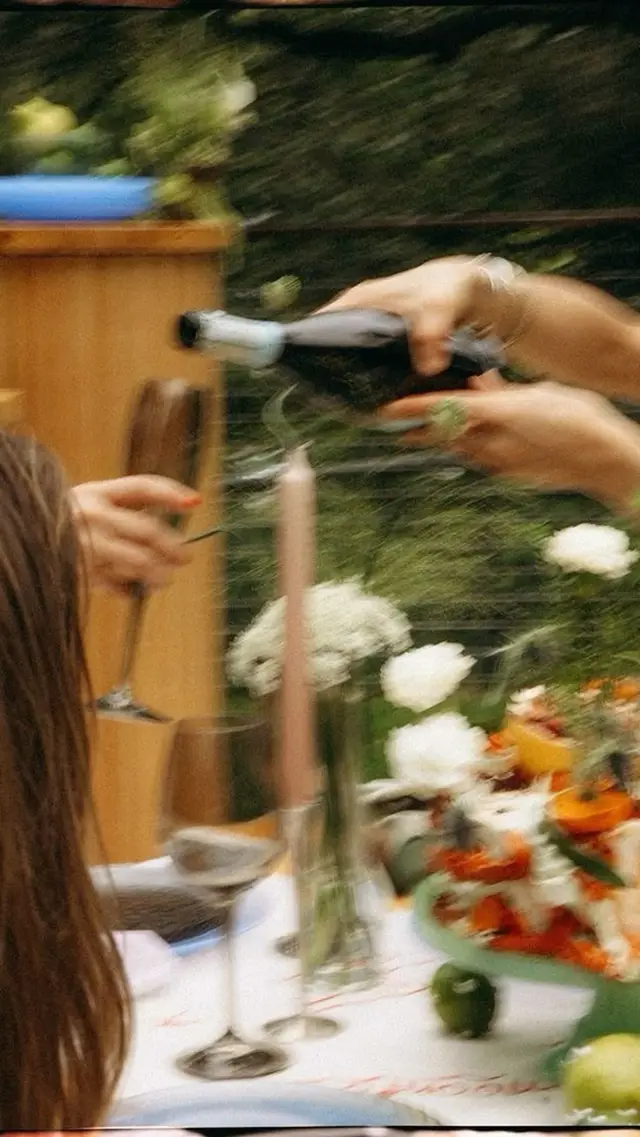 Motion-blur: wine being poured at an outdoor table with floral centerpiece