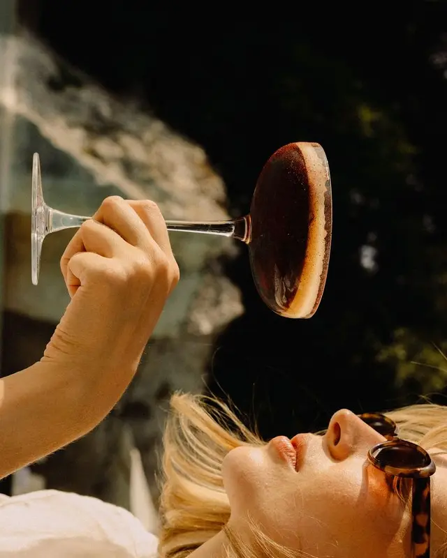 Golden-hour espresso martini in coupe held over reclining figure