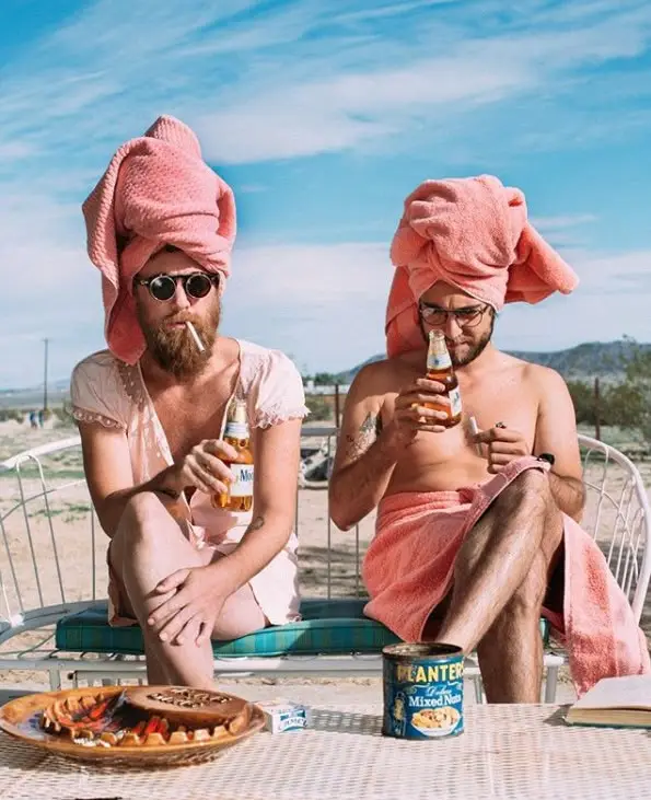 Two friends in pink towels drinking Modelo in desert lounge