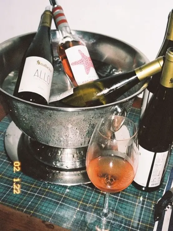 Stainless-steel ice bucket with rosé and 'ALLO' wine on tartan tablecloth