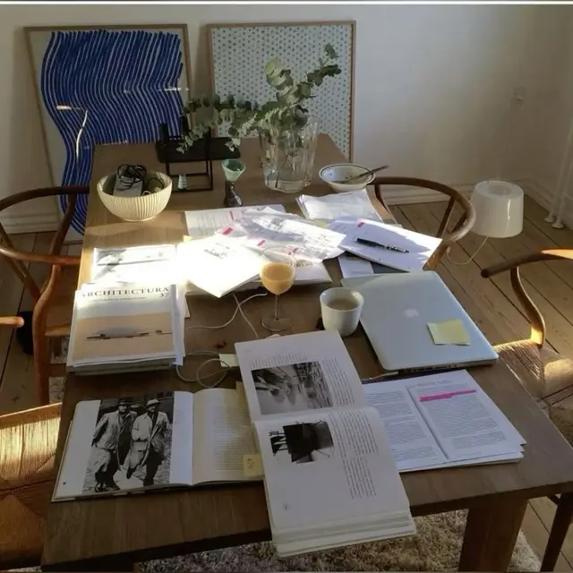 Sunlit dining-table workspace with architecture books and closed laptop