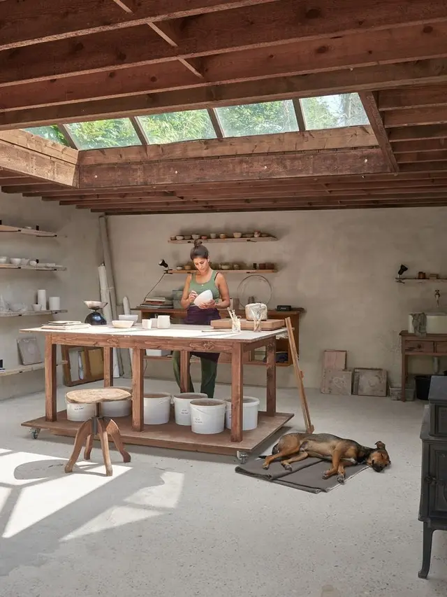 Sunlit pottery studio with skylights and wooden workbench