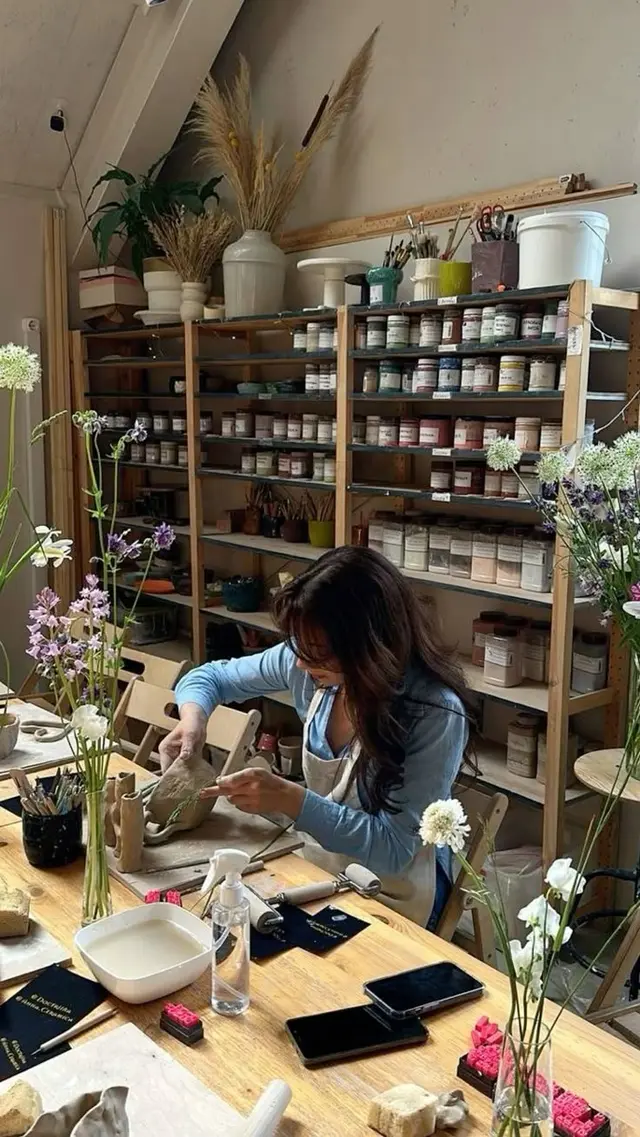 Hand-building Ceramics in a Sunlit Studio with Shelves of Glaze Jars
