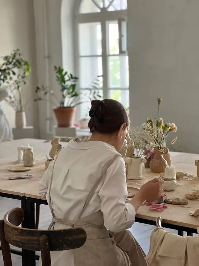 Sunlit pottery studio table with person shaping clay