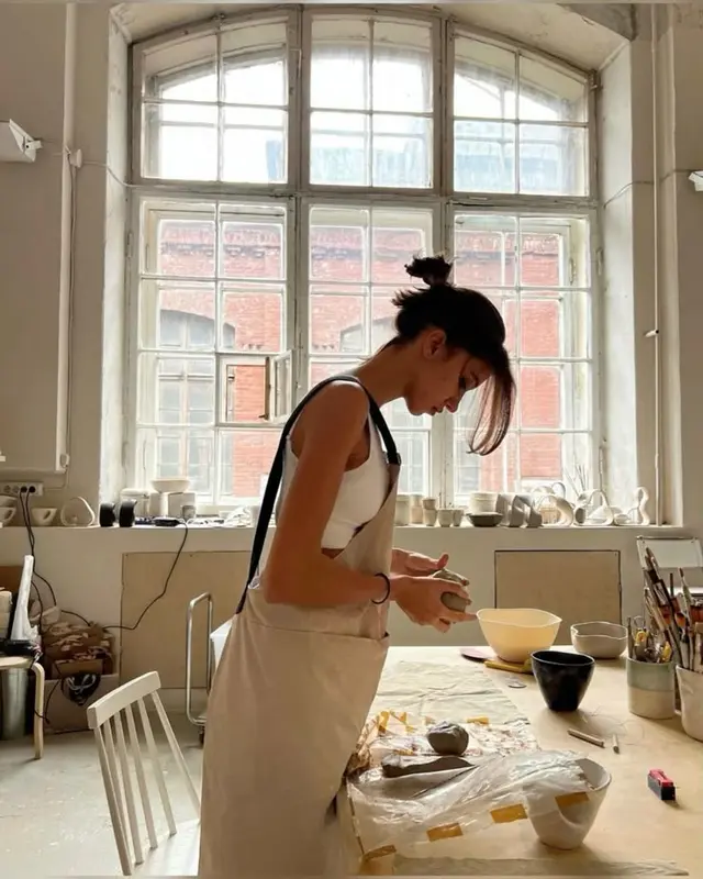 Sunlit pottery studio — hand-building clay at arched window