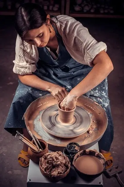 Potter shaping a clay cup on a wheel