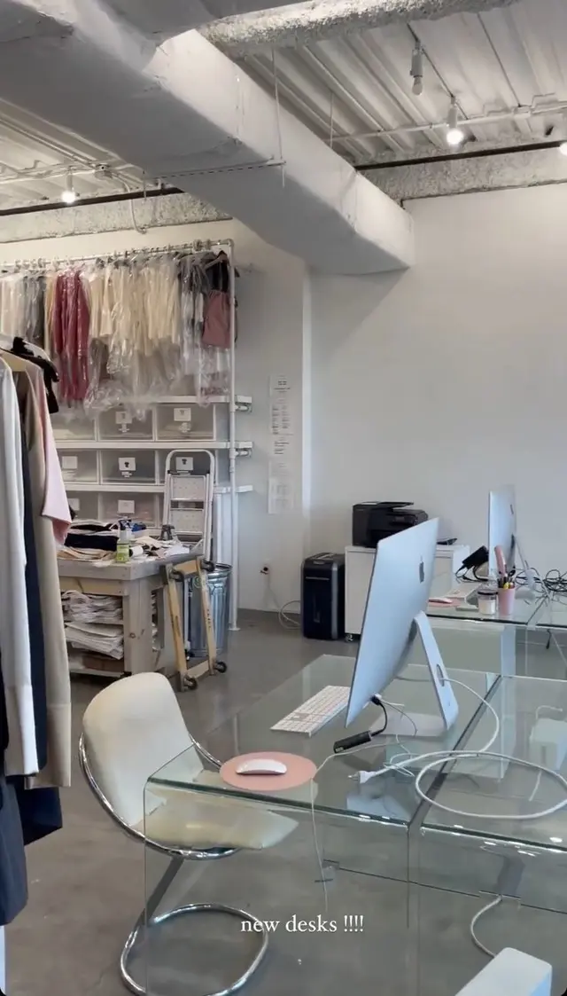 Open-plan fashion studio with glass desks and garment rack