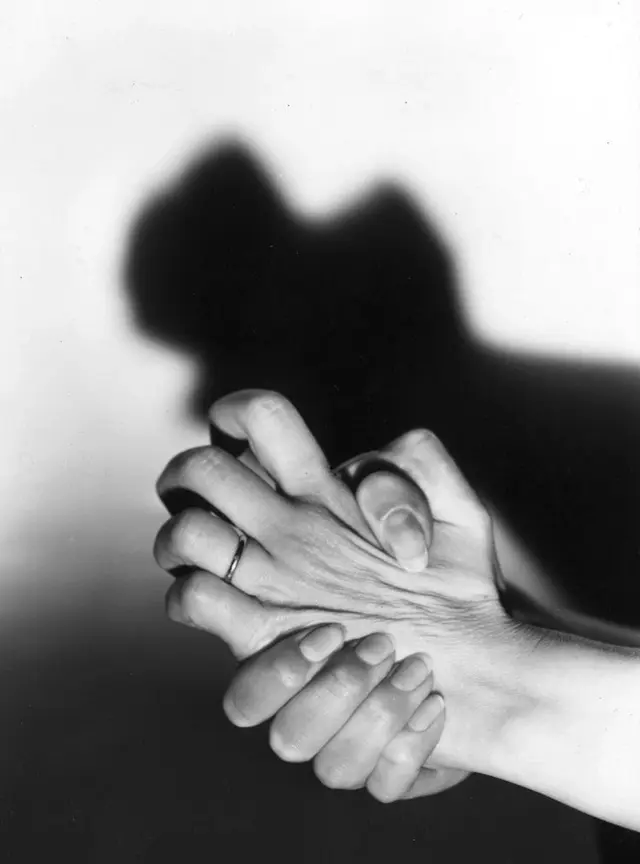 Black-and-white close-up of clasped hands (The Atlantic illustration)