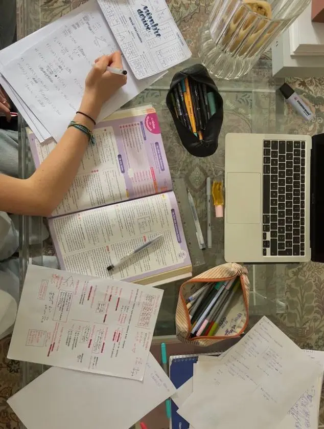 Overhead study workspace with laptop, purple textbook and handwritten notes