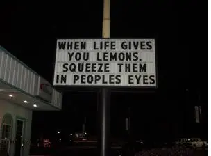 Nighttime roadside marquee sign reading a sarcastic proverb
