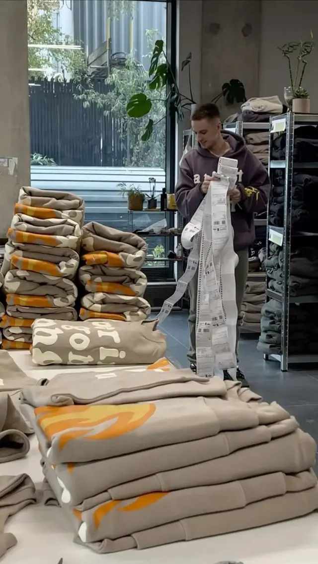 Retail stockroom with stacked beige hoodies and long thermal receipts