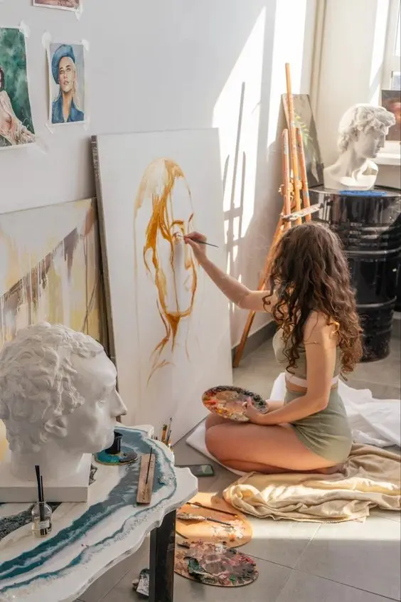 Artist Painting Portrait in Sunlit Studio with Classical Busts