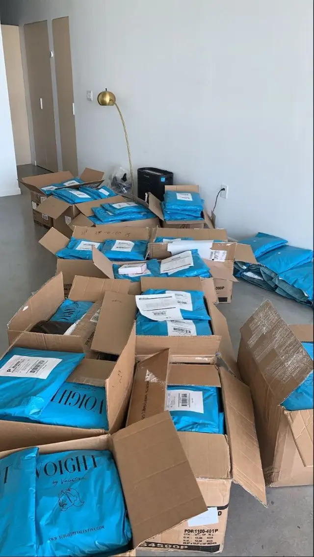 Apartment floor stacked with cardboard boxes and blue VOIGHT poly mailers