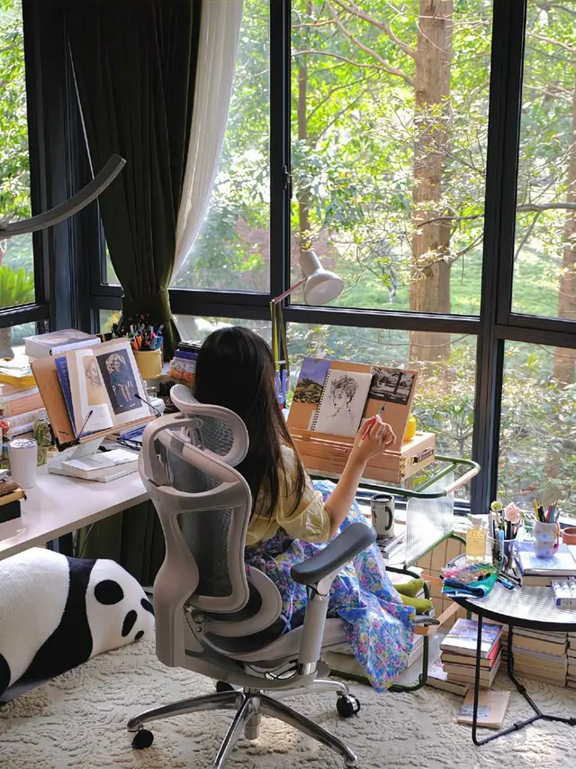 Sunlit art workspace by floor-to-ceiling windows with mesh swivel chair
