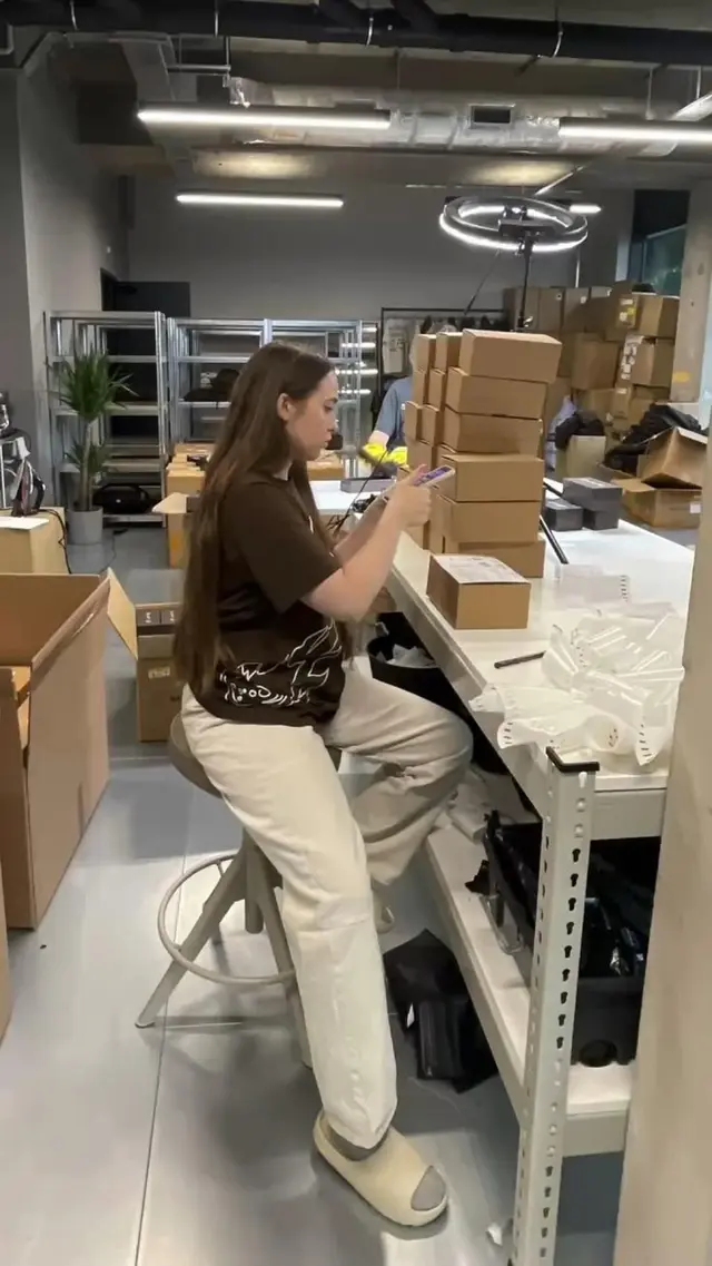 Warehouse packing station with stacked corrugated mailer boxes and ring light