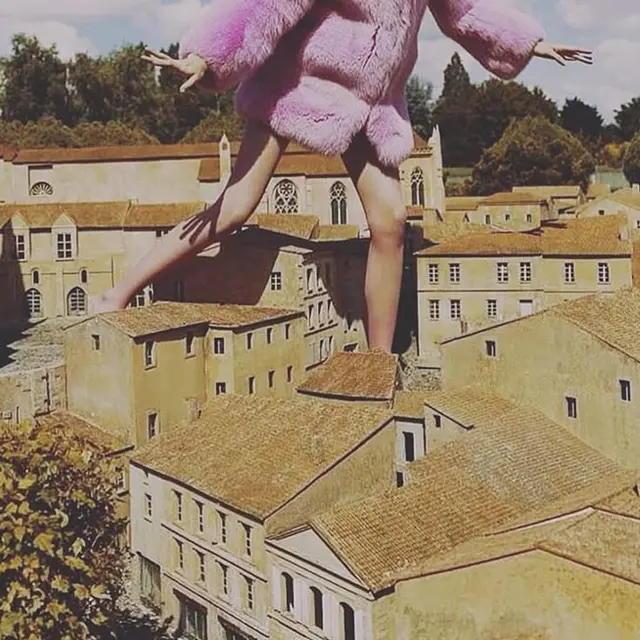 Pink faux-fur coat giant stepping over miniature Mediterranean village