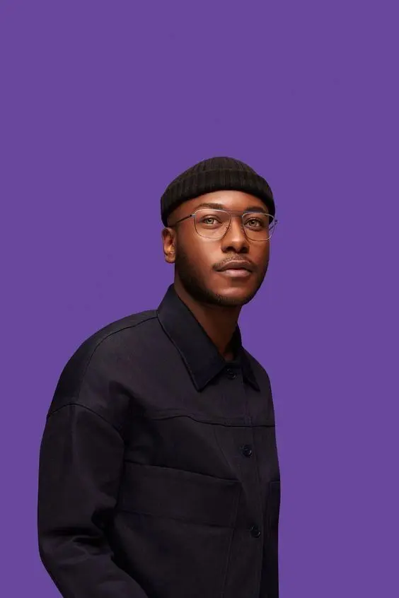 Minimal Studio Portrait — Beanie and Clear-Rim Glasses on Purple Background