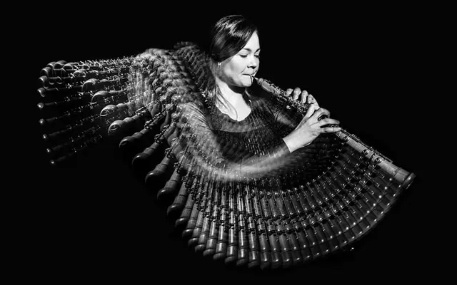 Black-and-white long-exposure portrait of woman playing a pan flute