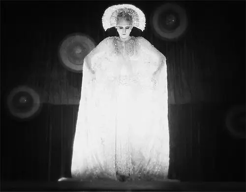 Vintage theatrical portrait — performer in halo headpiece and floor-length cloak