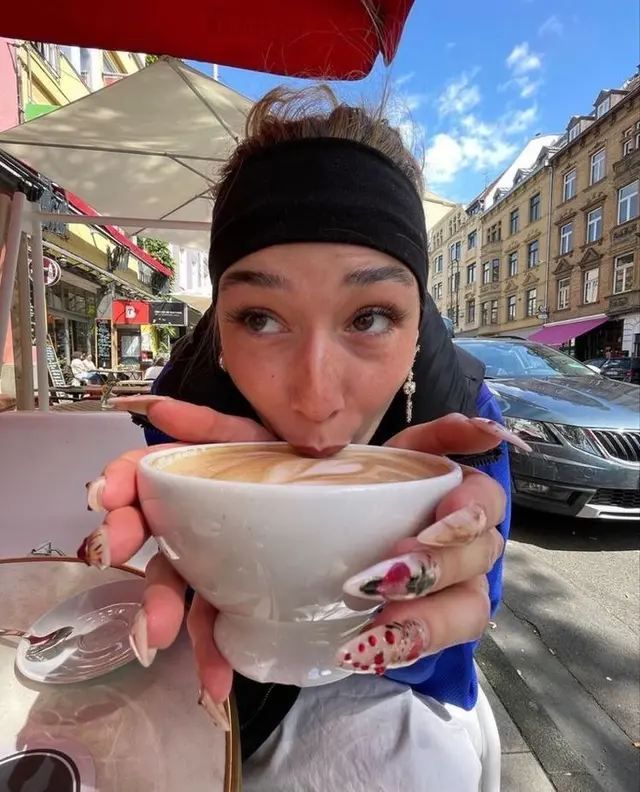 Close-up: person sipping latte at outdoor city café