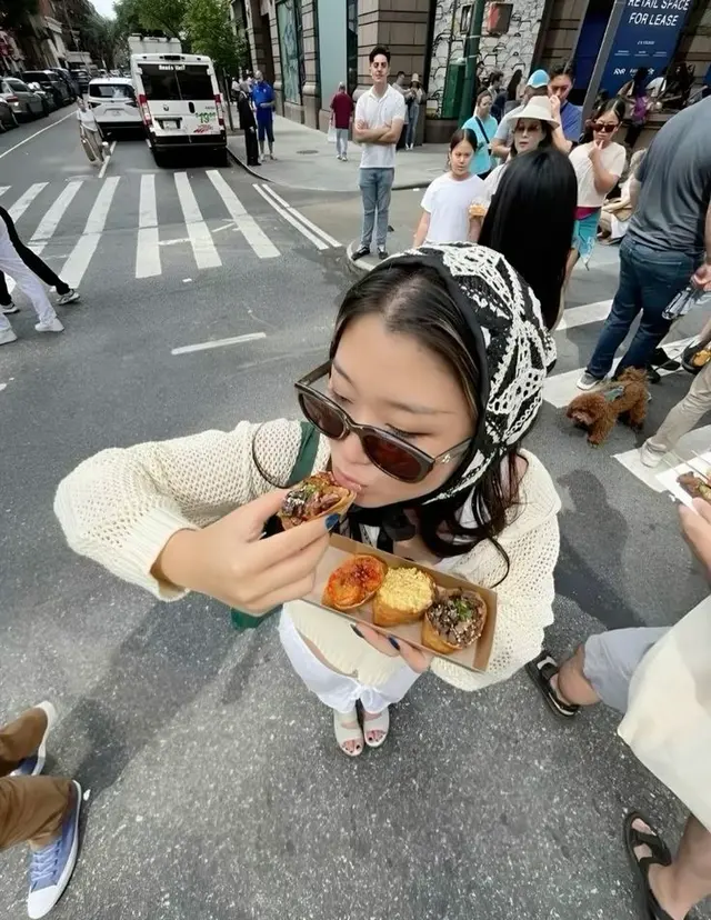 Person with lace headscarf eating mini tarts on city crosswalk — overhead street photo
