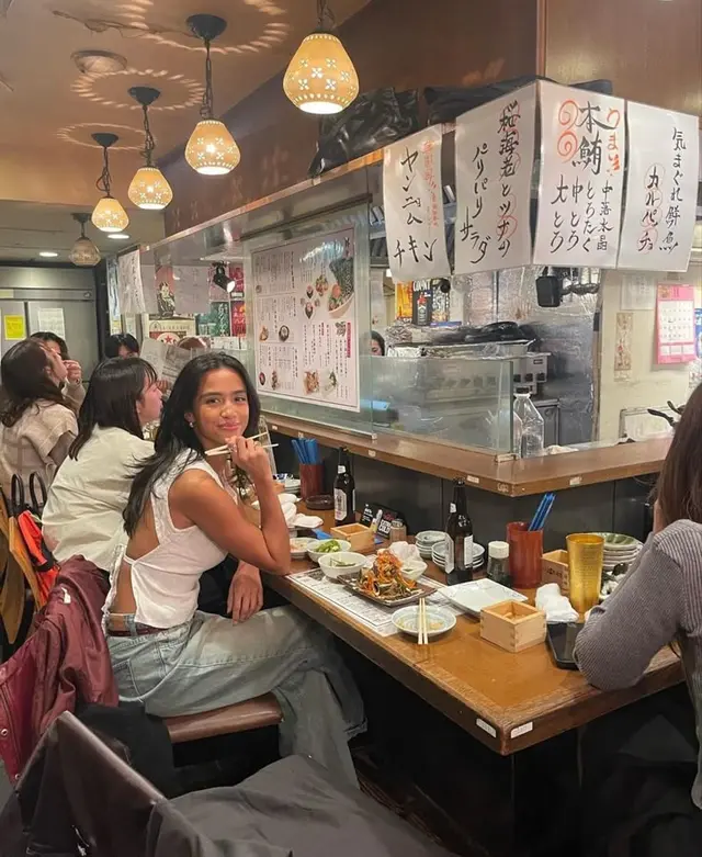 Izakaya counter with hanging handwritten menus and warm pendant lights