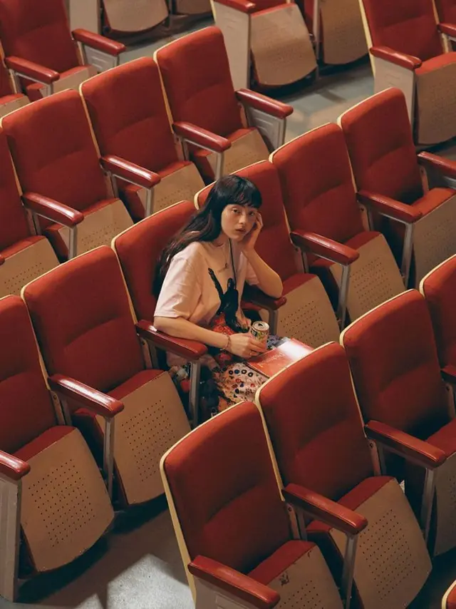 Solitary woman in red auditorium — overhead cinematic portrait