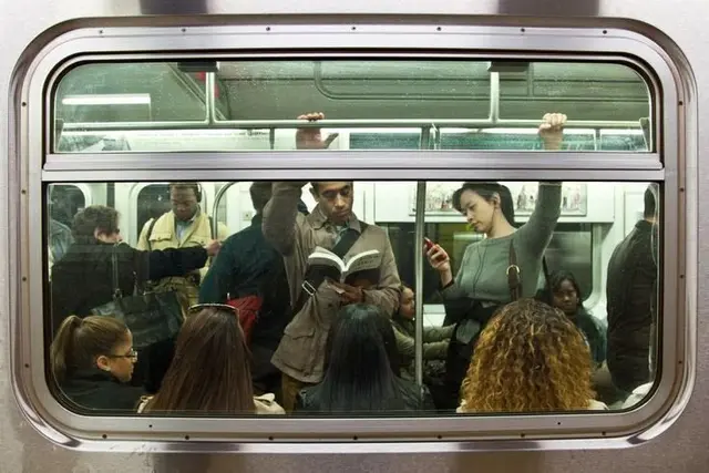 Commuters Reading and Using Phones Through Subway Window