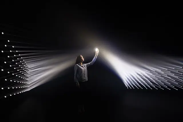 Person Holding Glowing Orb Between Converging LED Light Arrays