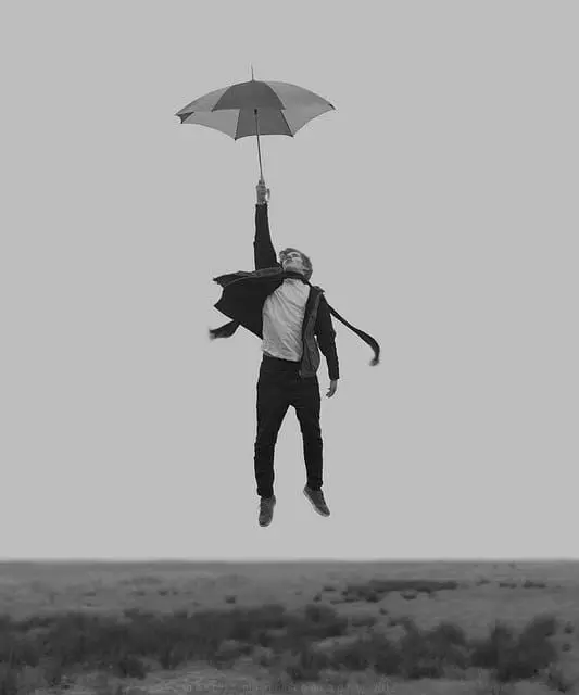 Man Levitating with Umbrella Above Open Field — Black & White Concept Photo
