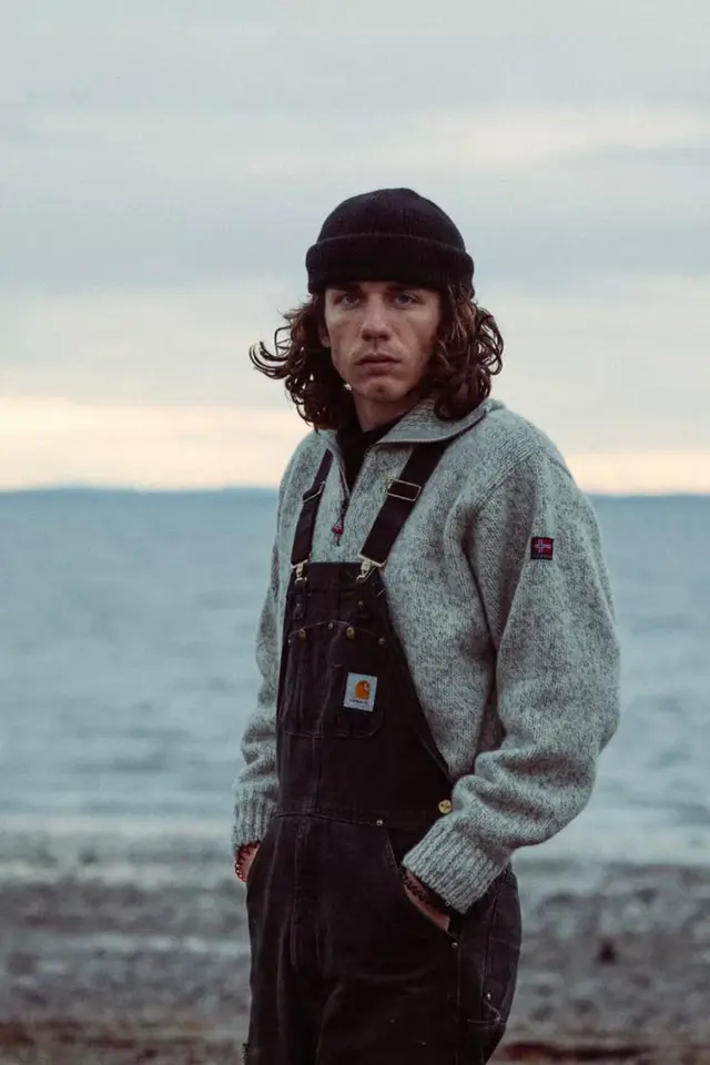 Coastal portrait — black beanie, Carhartt overalls, Norwegian wool sweater