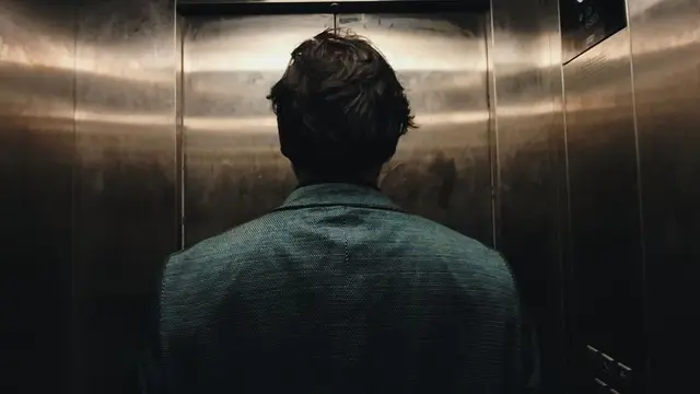 Back view in stainless-steel elevator — moody cinematic still