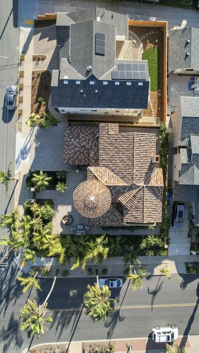 Aerial view — Mediterranean clay-tile house with circular turret and neighboring solar-roo