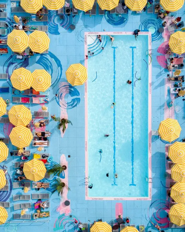 Top-down pastel lap pool with yellow-striped umbrellas