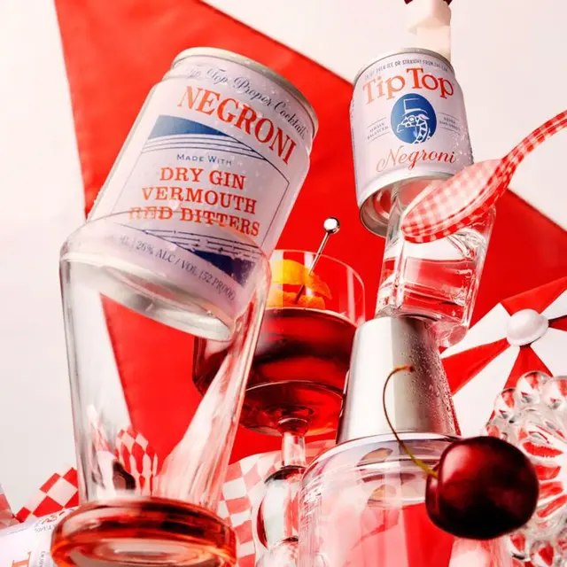 Canned Negroni still life with coupe glass, cherry and gingham ribbon