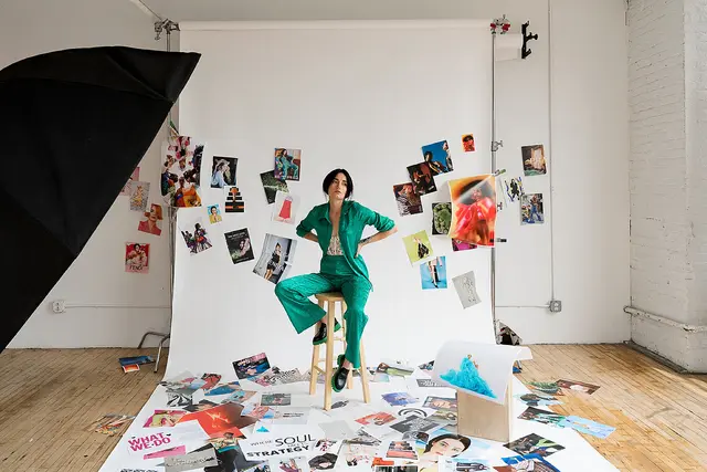 Studio editorial — woman in emerald green suit amid magazine collage (What is Lucky Girl S