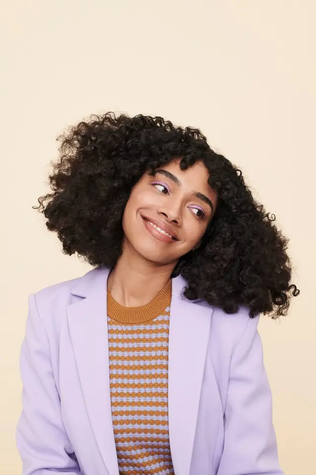 Prose article hero — studio portrait of model with dense natural curls