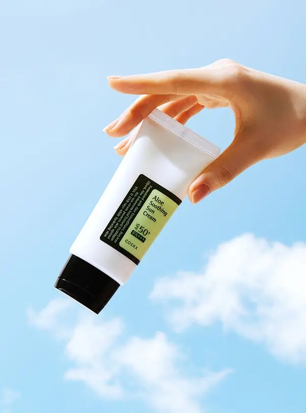 COSRX Aloe Soothing Sun Cream SPF50+ tube held against blue sky — See My Skin product shot