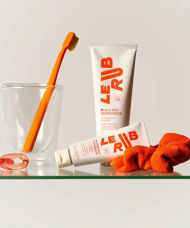 LE RIB All-Day Sunscreen still life with orange toothbrush and scrunchie
